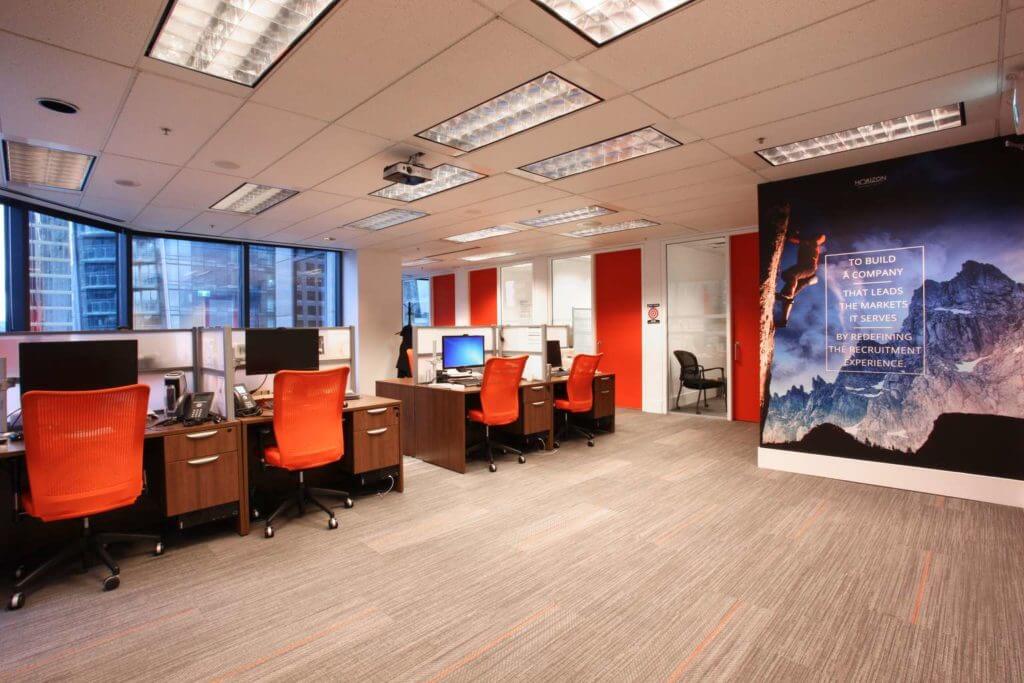 Open work area in the modern corporate office with the orange accents and the motivational wall print.