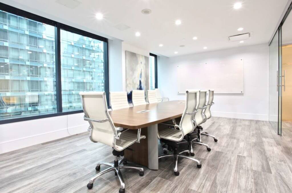 Modern corporate office boardroom with wood table and white chairs.