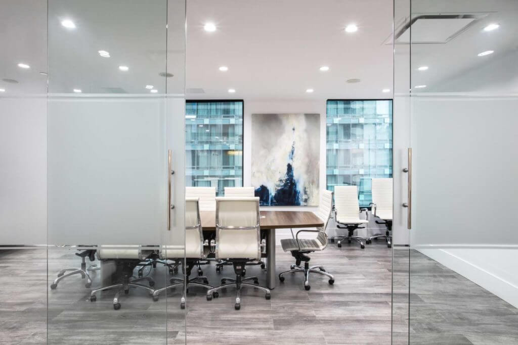 Modern boardroom with sliding glass doors and white chairs.