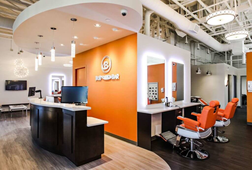 Modern reception desk with company logo, custom reception desk and LED mirrors on the orange accent wall.